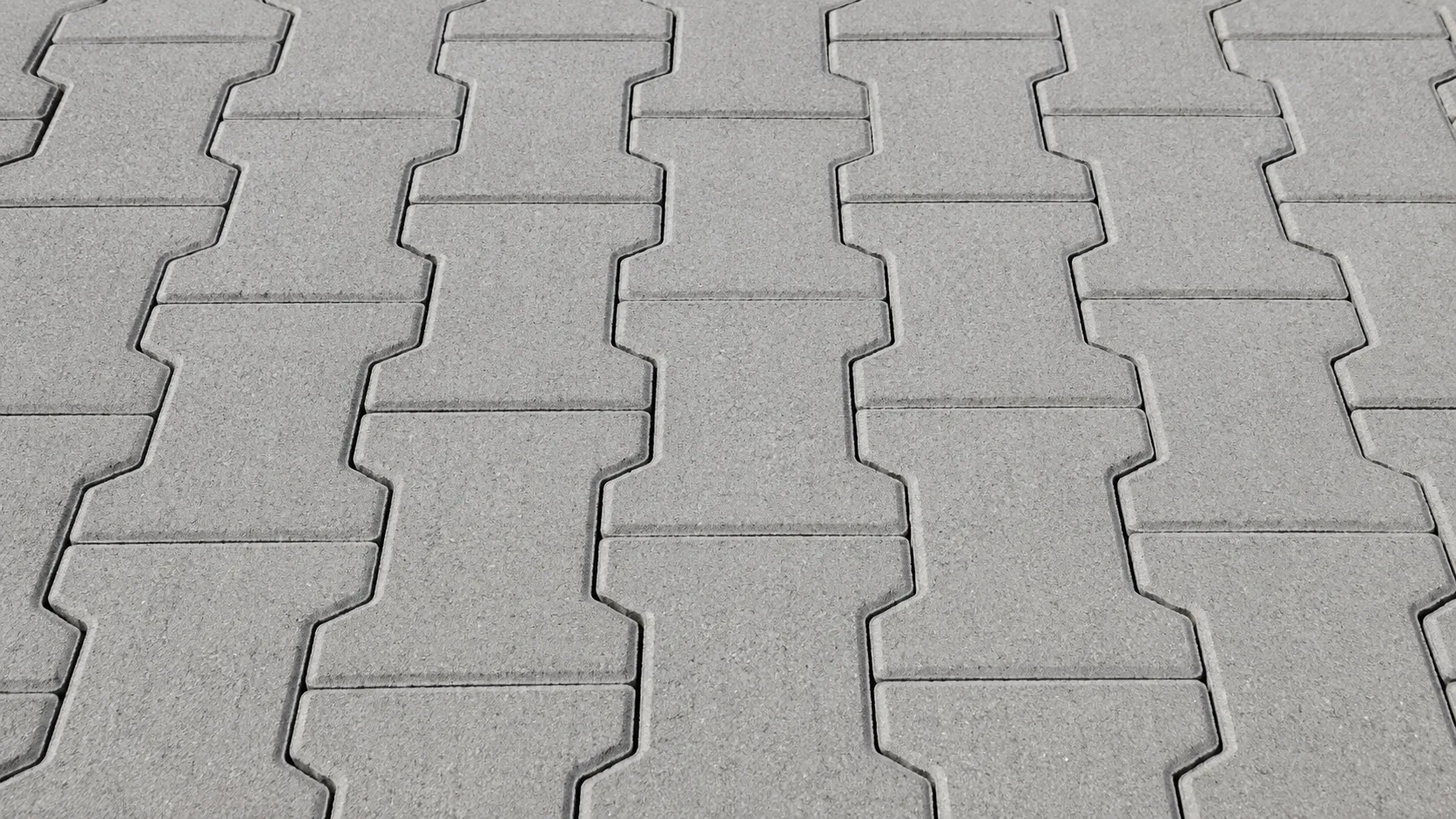 Gri beton çift T formundaki kilit taşlarının düzenli ve tekrar eden döşeme deseniyle gösterildiği yakın plan ürün görseli.