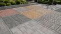 Dış mekanda sergilenen gri, kırmızı ve sarı tonlarda farklı beton parke taşı çeşitleri.